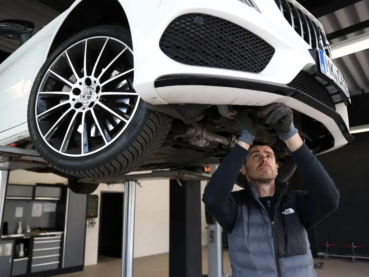 Technische Fahrzeugprüfung auf der Hebebühne in der Prüfhalle von Gutachter Koop